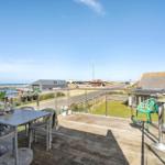 Terrasse mit Tisch, Stühlen und Blick auf Hafen und Straße.