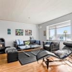 Wohnzimmer mit Sofa, Liegesofa und Kamin. Fenster mit Blick auf Wasser.