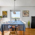 Esszimmer mit Tisch, Stühlen und Fensterblick auf Grasland.