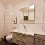 Badezimmer mit Waschbecken, Spiegel, Toilette und Dusche.