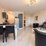 Wohnung mit Essbereich, Küche und Wohnzimmer mit Sofa und Sessel.