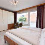 Schlafzimmer mit Doppelbett, Kleiderschrank und Balkonansicht.