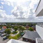 Blick von Balkon auf Stadt mit Grünflächen und Parkplatz