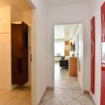 Flur mit Blick in Bad und Wohnzimmer. Rote Schrankwand an der Wand.