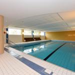 Innenpool mit Treppe, Sitzbänken und beleuchteten Wänden.