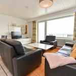 Wohn- und Essbereich mit Ledersofa, TV und Balkon.
