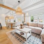 Wohn- und Essbereich mit Holzboden, Sofa, Tisch und Kücheninsel.