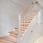 Holzgetreppe mit weißem Geländer führt zur oberen Etage.