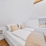 Schlafzimmer mit Doppelbett, Fenster und Fernseher an der Wand.