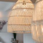 Rattan-Lampen hängen im Wohnbereich. Wandbild mit Tiermotiv im Hintergrund.