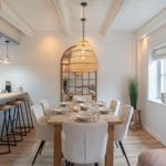 Essbereich mit Holztisch, Stühlen und Kücheninsel. Decke mit Balken und Fenster.