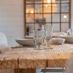 Holztisch mit Geschirr und Gläsern, Hintergrund mit Holzfenster und Lampen