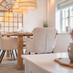 Essbereich mit Holztisch, Stühlen und Deckenleuchten. Fenster mit Jalousie und Pflanzen.