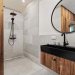 Bad mit Dusche, Waschbecken und runden Spiegel