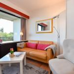 Wohnzimmer mit Sofa, Sessel und Balkonansicht.