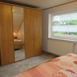 Schlafzimmer mit Kleiderschrank, Fenster und Bett.