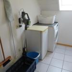 Waschraum mit Waschmaschine, Wäschekorb und Staubsauger.