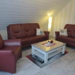 Wohnzimmer mit zwei Sofas, Sessel und Couchtisch auf Teppich