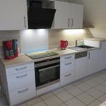 Küche mit weißen Schränken, Edelstahlherd und rotem Wasserkocher.