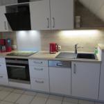 Küche mit weißen Schränken, Edelstahlspüle und rotem Wasserkocher.