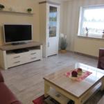 Wohnzimmer mit Fernseher, Couch, Tisch und Fenster.