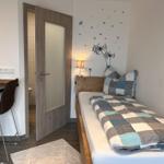 Schlafzimmer mit Bett, Schreibtisch und Tür zum Bad.