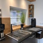 Küche mit Spüle, Kaffeemaschine und Pflanze an Fenster