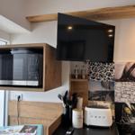 Küche mit Mikrowelle, Toaster und Fernseher an der Wand.