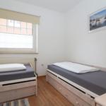 Zimmer mit zwei Einzelbetten, Fenster und Wandbild.