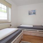 Zimmer mit zwei Betten, Fenster und Wandbild.