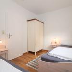 Zimmer mit zwei Betten, Kleiderschrank und Nachttischen mit Lampen.