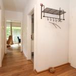 Flur mit Holzboden, Garderobe und Blick in Wohn- und Schlafzimmer.