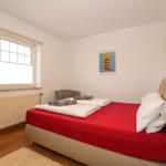 Schlafzimmer mit Bett, Fenster und Wandbildern.