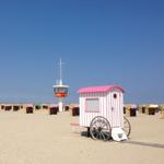 Strand mit Strandkörben und Rettungswache im Hintergrund.