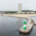 Hafen mit Leuchtturm, Strand und Hochhaus im Hintergrund.