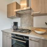 Küche mit Kochfeld, Backofen und Dunstabzug.