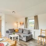 Wohn- und Essbereich mit Sofa, Tisch und Stühlen. Durchgang zur Schlafstube.