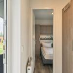 Schlafzimmer mit Bett und Kleiderschrank. Terrasse mit Sitzgelegenheit und Blick auf Grünfläche.