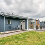 Moderne Ferienhaus mit Terrasse und Garten. Glastüren führen ins Innere.