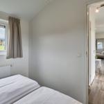 Zimmer mit Doppelbett und Fenster. Blick in die Küche und Wohnbereich.