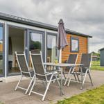 Terrasse mit Tisch und Stühlen vor modernem Ferienhaus.