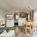 Wohn- und Essbereich mit Küche und Schlafzimmer im Hintergrund.