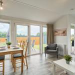 Wohn- und Essbereich mit Tisch, Stühlen und Sitzgelegenheiten. Durchgang zur Terrasse.