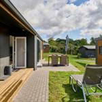 Terrasse mit Liegestühlen und Tisch. Hinterhof mit Gras und weiteren Häusern.