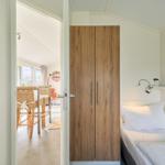 Schlafzimmer mit Bett, Kleiderschrank und Blick in Essbereich.