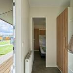 Schlafzimmer mit Bett und Kleiderschrank. Durchgang zur Terrasse mit Liegestuhl.