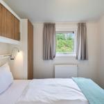 Schlafzimmer mit Bett, Fenster und Holzschränken.