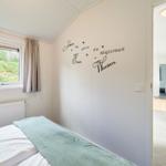 Schlafzimmer mit Bett, Fenster und Wanddekoration. Blick in die Küche.