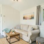 Wohnzimmer mit Sofa, Couchtisch und Fensterblick auf Grün.