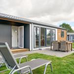 Moderne Ferienwohnung mit Terrasse, Liegen und Essgruppe im Freien.